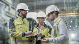 Drei Arbeiter mit Tablet in Fabrikhalle