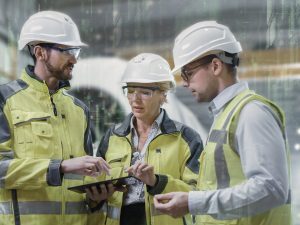 Drei Arbeiter mit Tablet in Fabrikhalle